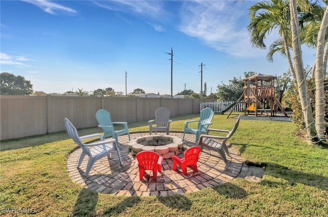 view of yard with a patio, a fire pit, a fenced backyard, and a playground