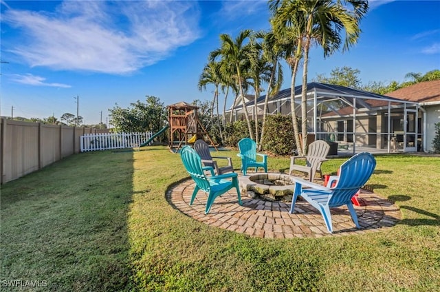 view of yard with a fenced backyard, a playground, glass enclosure, a fire pit, and a patio area