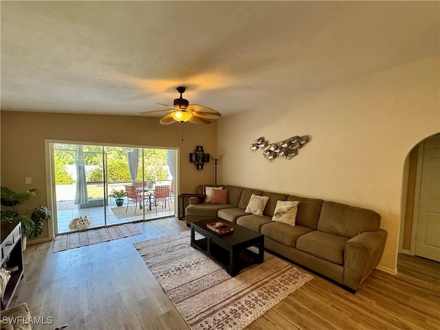 living room with arched walkways, wood finished floors, and a ceiling fan