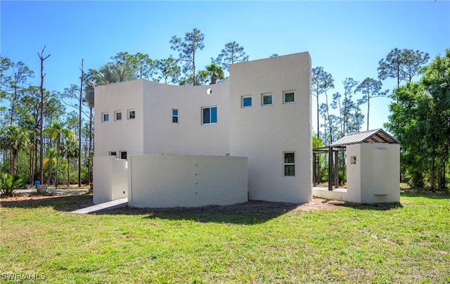 back of house with a lawn and stucco siding