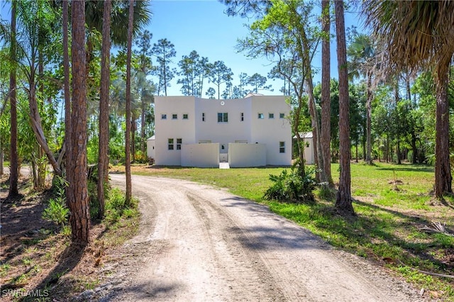 exterior space with stucco siding, a yard, and dirt driveway