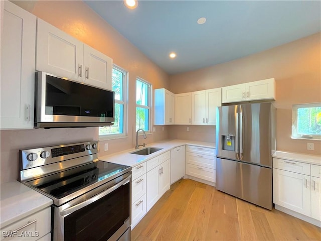 kitchen with light countertops, white cabinets, appliances with stainless steel finishes, and a sink