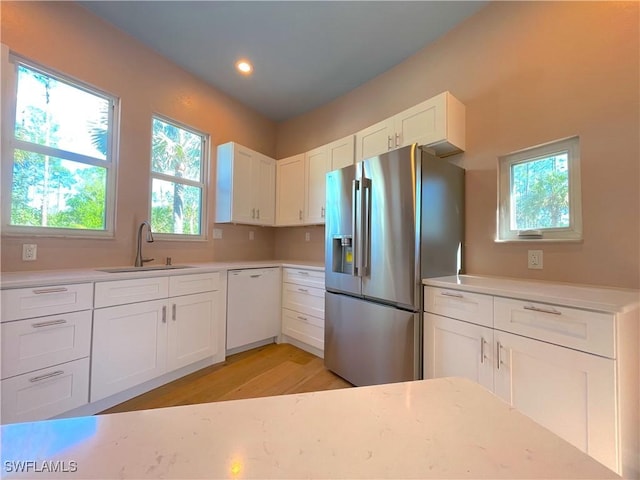 kitchen featuring a sink, dishwasher, stainless steel fridge with ice dispenser, and light countertops