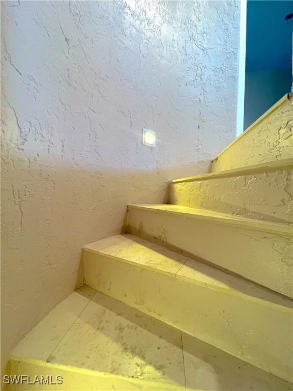 staircase featuring tile patterned flooring and a textured wall