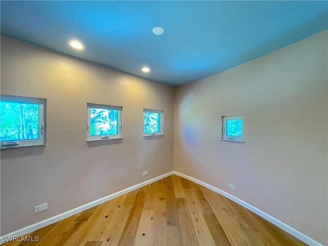 spare room with recessed lighting, baseboards, plenty of natural light, and wood finished floors