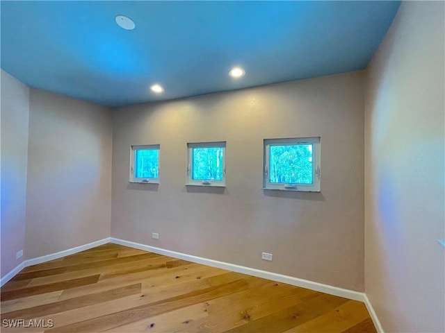 unfurnished room featuring recessed lighting, wood finished floors, and baseboards