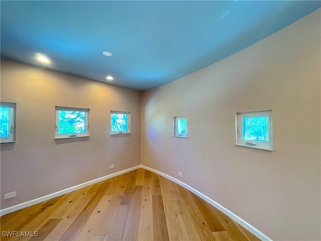 spare room featuring a wealth of natural light, recessed lighting, light wood-style floors, and baseboards