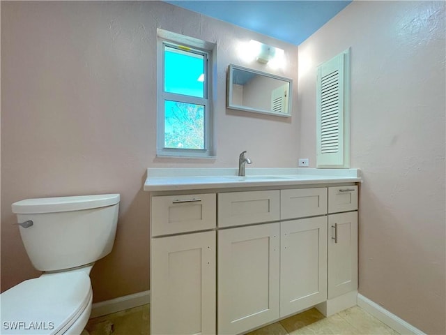 bathroom with toilet, vanity, and baseboards