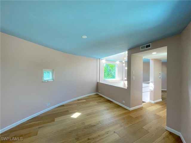 spare room with wood finished floors, visible vents, and baseboards