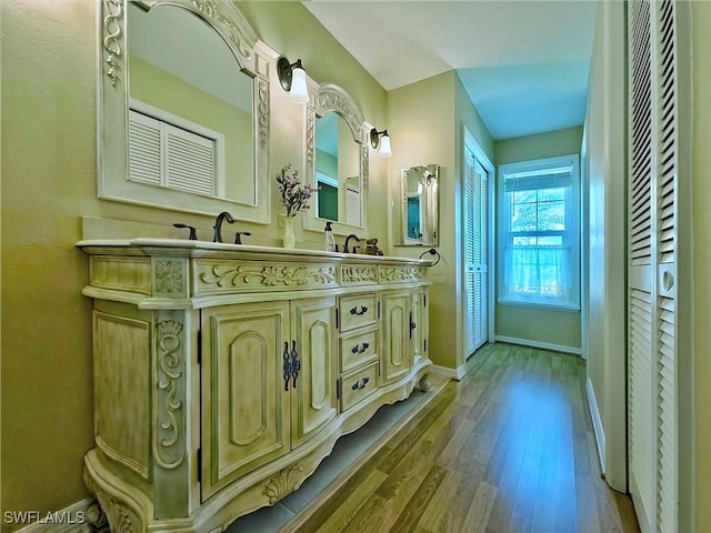 bathroom with double vanity, baseboards, and wood finished floors