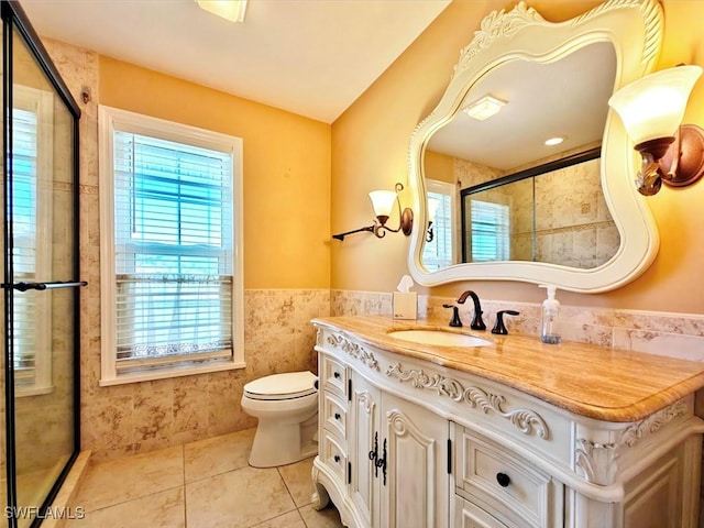 bathroom with tile walls, wainscoting, tile patterned flooring, and a healthy amount of sunlight