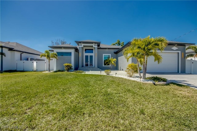 back of property with stucco siding, a lawn, concrete driveway, and fence