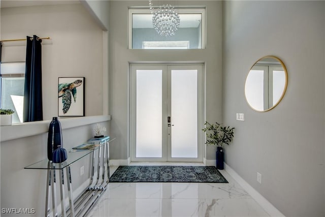 foyer entrance with a chandelier, marble finish floor, french doors, and baseboards