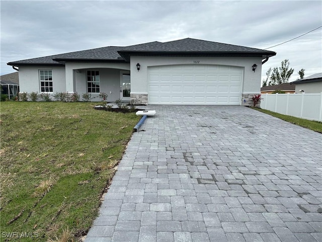 view of front facade with a front lawn, decorative driveway, fence, and stucco siding