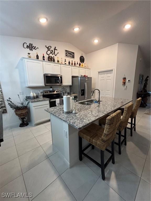 kitchen with stone counters, a breakfast bar area, stainless steel appliances, and a sink