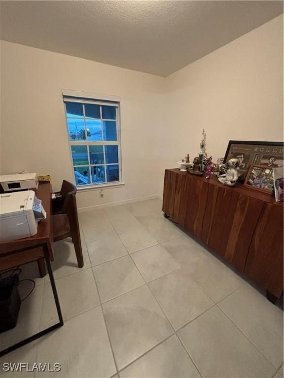 office area featuring light tile patterned floors, baseboards, and a textured ceiling