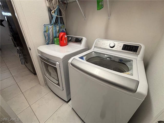 laundry area featuring light tile patterned flooring, laundry area, and washing machine and clothes dryer