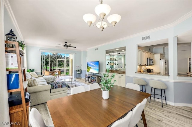 dining area featuring light wood finished floors, visible vents, baseboards, ornamental molding, and ceiling fan with notable chandelier