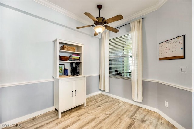 empty room featuring crown molding, light wood-style flooring, a ceiling fan, and baseboards