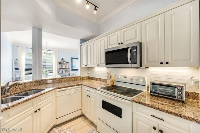 kitchen with backsplash, ornamental molding, white appliances, and a sink