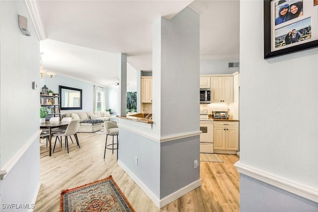 kitchen with stainless steel microwave, visible vents, a breakfast bar area, cream cabinetry, and white electric stove