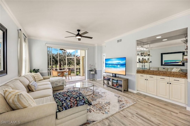 living area featuring light wood-style floors, visible vents, and ornamental molding