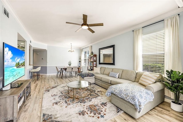 living room with visible vents, ceiling fan with notable chandelier, crown molding, and wood finished floors