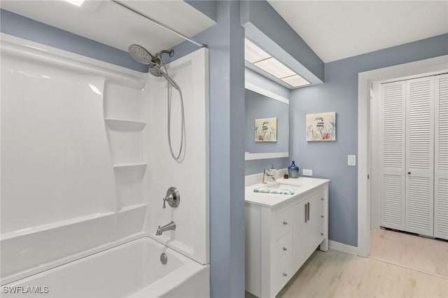 bathroom with bathtub / shower combination, vanity, a closet, and baseboards