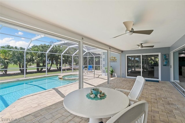 view of pool featuring ceiling fan, a pool with connected hot tub, glass enclosure, and a patio