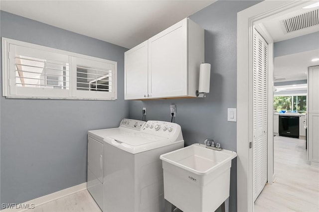 washroom with visible vents, washer and clothes dryer, a sink, cabinet space, and baseboards