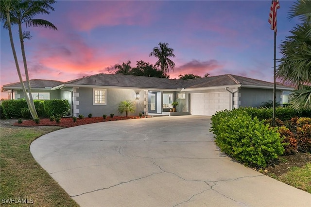 ranch-style home featuring a tile roof, stucco siding, concrete driveway, and a garage