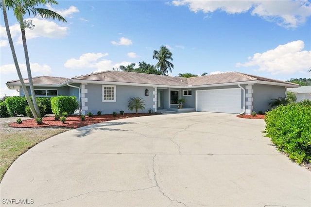 ranch-style home featuring a tile roof, stucco siding, an attached garage, and concrete driveway