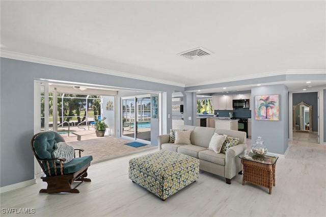 living room with light wood-style floors, crown molding, baseboards, and visible vents