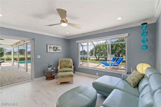 living area with wood finished floors, a ceiling fan, baseboards, and ornamental molding