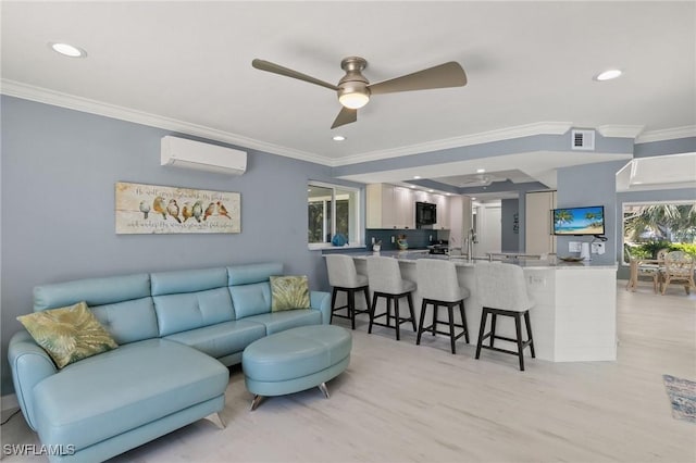 living area featuring visible vents, an AC wall unit, ornamental molding, a ceiling fan, and light wood-style floors