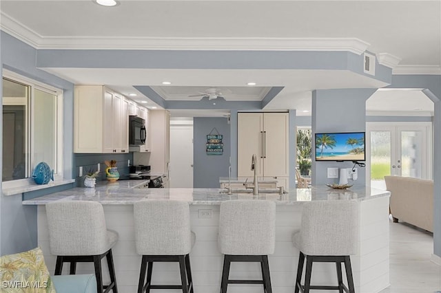 kitchen with black appliances, light stone counters, a sink, a peninsula, and crown molding