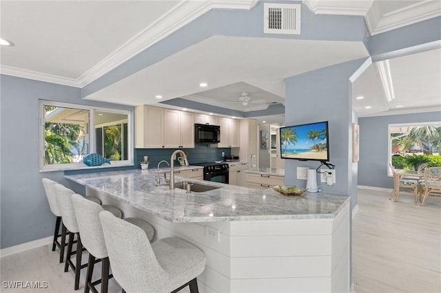 kitchen featuring light stone counters, visible vents, a sink, black microwave, and crown molding