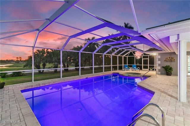 pool at dusk with a patio area, glass enclosure, and a pool with connected hot tub