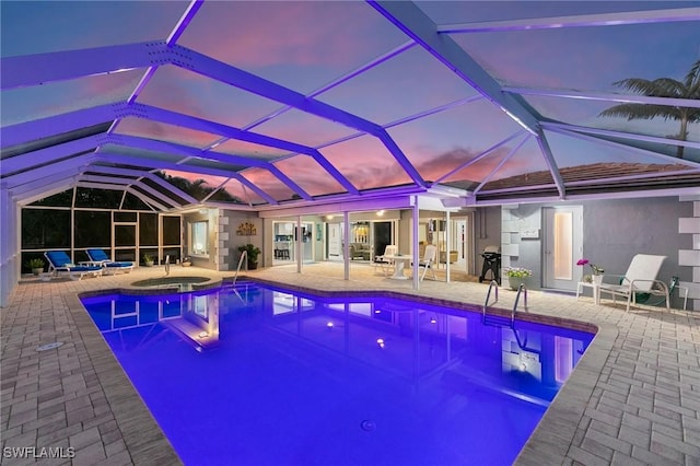 view of pool with a patio area, grilling area, glass enclosure, and a pool with connected hot tub