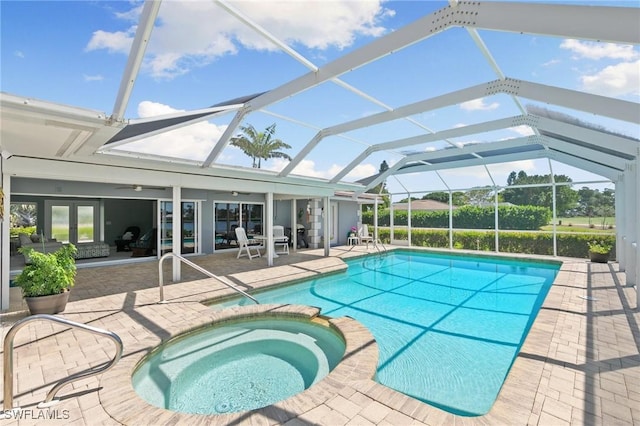 view of pool with a patio area, glass enclosure, and a pool with connected hot tub