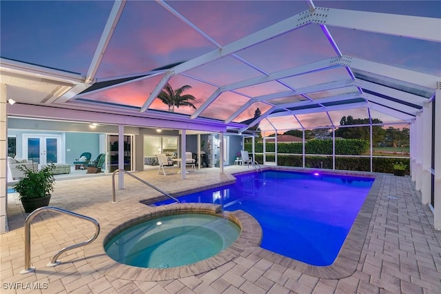 view of swimming pool featuring a patio area, french doors, a pool with connected hot tub, and a lanai