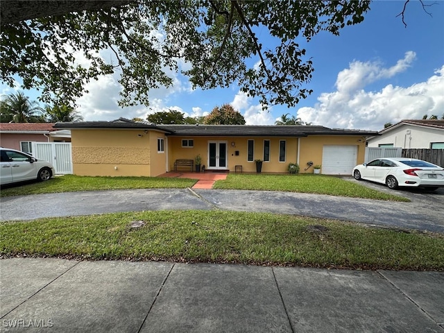 single story home with a front lawn, aphalt driveway, stucco siding, french doors, and an attached garage