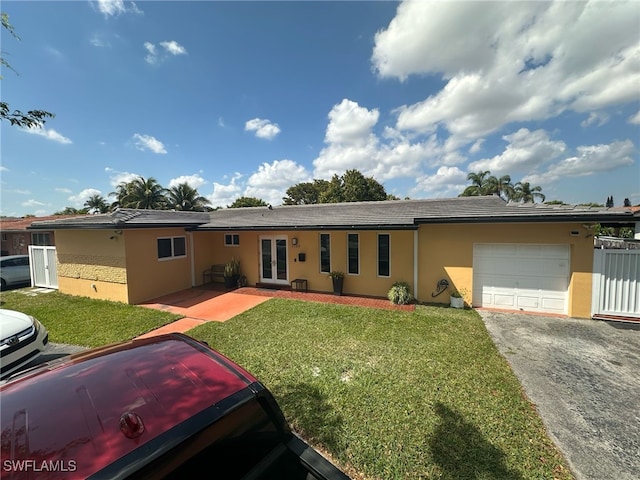 single story home with aphalt driveway, a front yard, stucco siding, french doors, and a garage