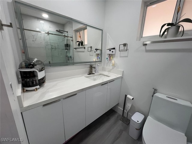 full bathroom featuring a marble finish shower, toilet, wood finished floors, and vanity