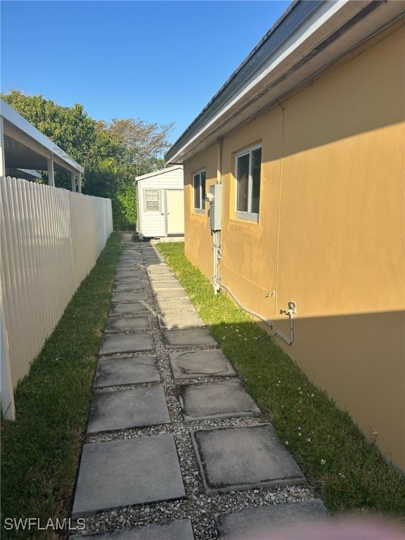 view of side of property featuring stucco siding, an outbuilding, and fence