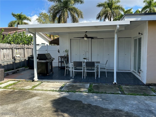 view of patio with outdoor dining area, a grill, a ceiling fan, and fence