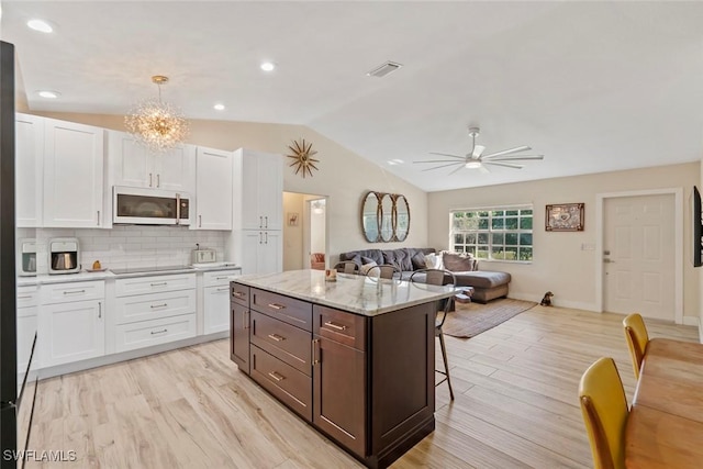 17450 Taylor Rd, Alva, FL 33920 - kitchen featuring visible vents, open floor plan, white cabinets, white microwave, and vaulted ceiling