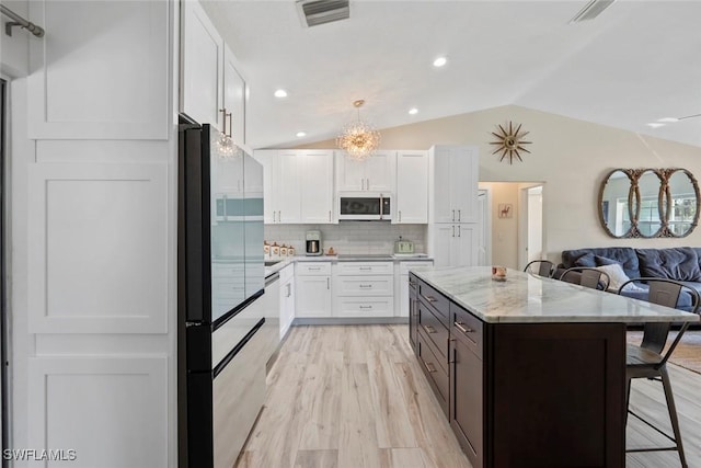 17450 Taylor Rd, Alva, FL 33920 - kitchen with a breakfast bar area, white microwave, visible vents, white cabinetry, and refrigerator with glass door