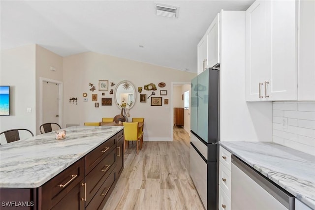 17450 Taylor Rd, Alva, FL 33920 - kitchen with visible vents, backsplash, lofted ceiling, freestanding refrigerator, and white cabinets