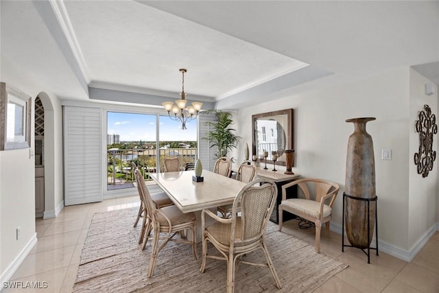 dining area featuring light tile patterned floors, baseboards, a raised ceiling, and an inviting chandelier